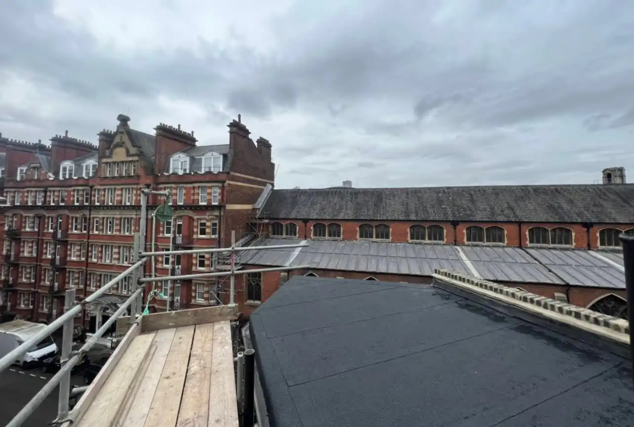 Elevated view across a large felt flat roof towards a London mansion block