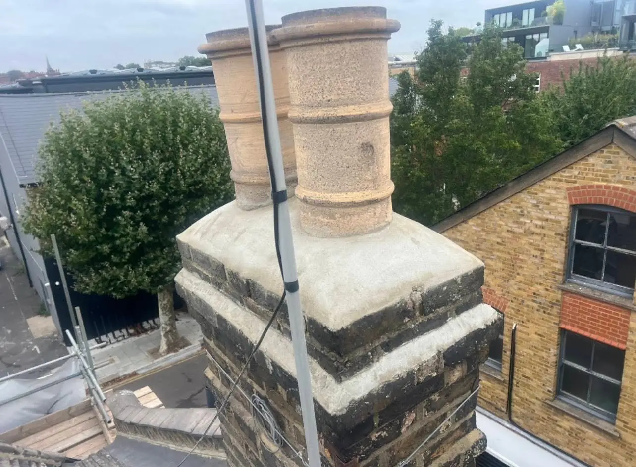 Newly repointed brick chimney stack with fresh flaunching on a London roof